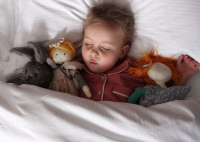 Girl asleep in a comfy bed with cuddly toys